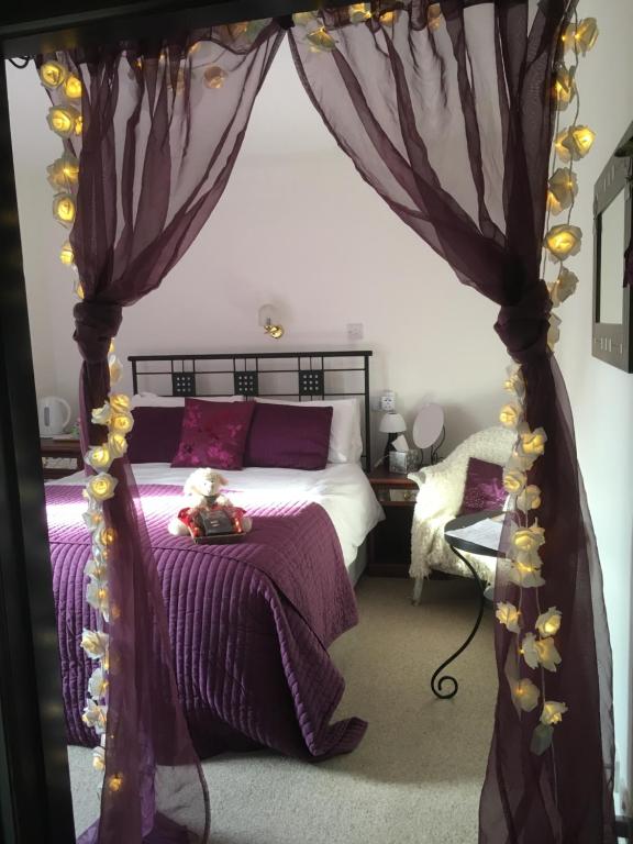 托明陶尔Gordon House的一间卧室配有一张带紫色床单的天蓬床