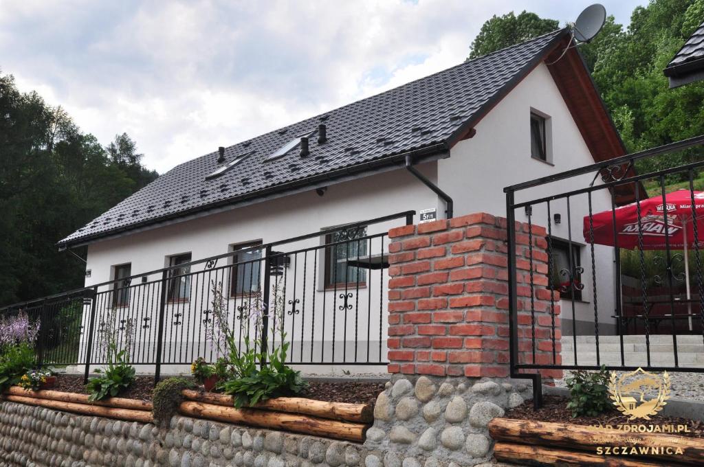 什恰夫尼察"Nad Zdrojami" Domek Kowalczyk 691-739-603的一间白色的小房子,设有黑色的围栏