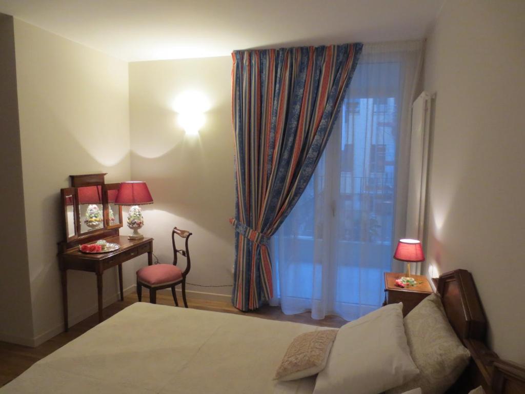 维罗纳卡萨潘维尼奥酒店的一间卧室配有一张床、一张书桌和一个窗户。