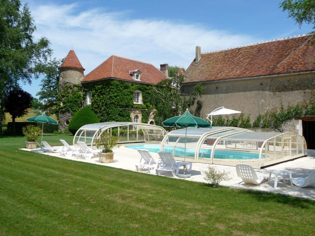 ChevannesChâteau de Ribourdin的房屋前的带椅子和遮阳伞的游泳池