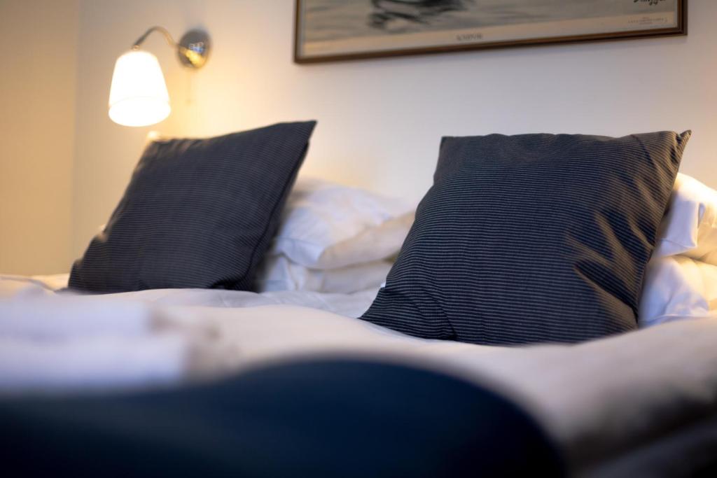AmmarnäsAmmarnäs Wärdshus的一张带两个黑色枕头和一盏灯的床