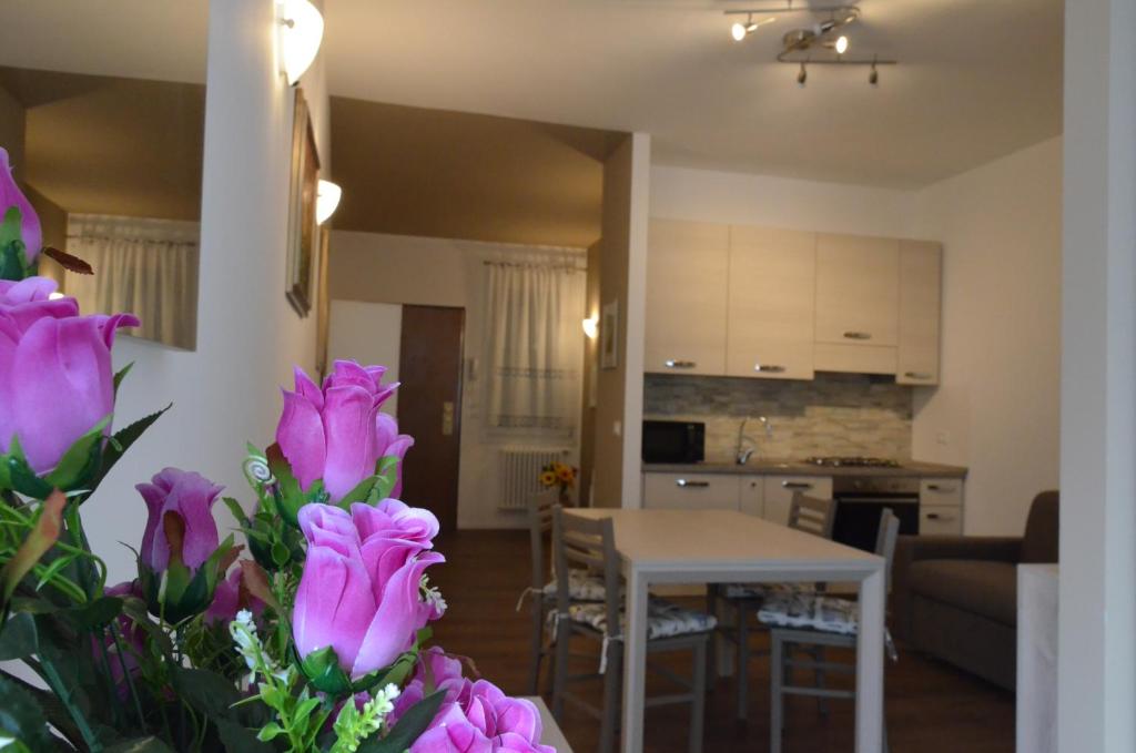 维琴察Residenza Ofelia的客厅以及带桌子和紫色鲜花的厨房