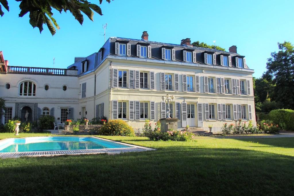 Asnières-sur-Oise勒克洛德菲住宿加早餐旅馆的一座大型白色房子,前面设有一个游泳池