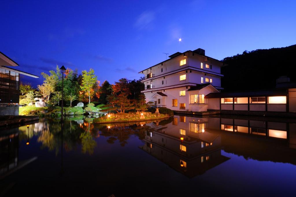 米泽市Onogawa Onsen Kajikaso的夜晚水里灯火通明的房子