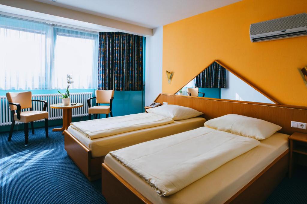 莱茵河畔威尔Hotel Central的酒店客房设有两张床和一张桌子。