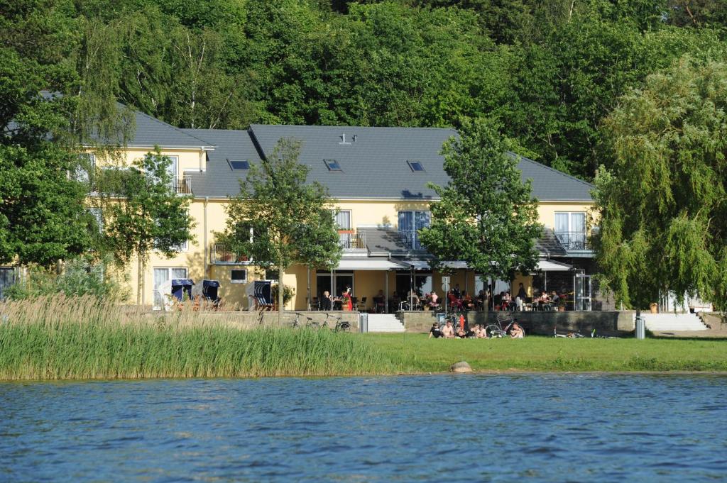 居斯特罗因塞尔湖湖畔酒店的一座建筑物,人们坐在水边的草上
