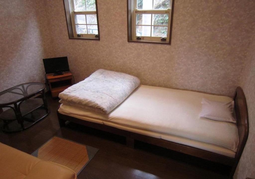 ŌbikiGuestHouse StrawberryFarm Shirasaki-Ⅱ / Vacation STAY19358的一间卧室配有一张床、一张桌子和两个窗户