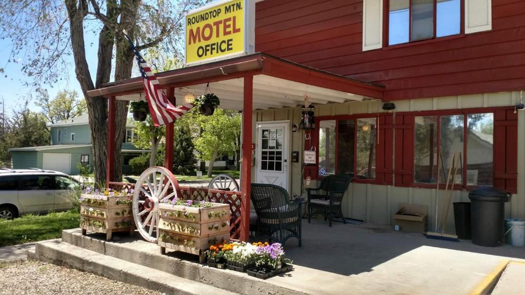 瑟莫波利斯Roundtop Mountain Vista - Cabins and Motel的前面有标志和鲜花的汽车旅馆办公室