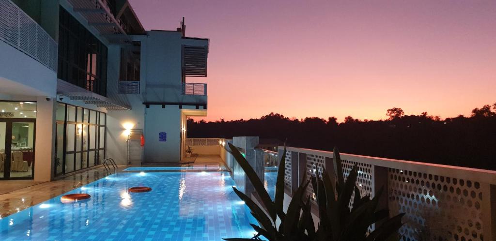 Kampong Mata Mata瓦法酒店和公寓的日落时分在建筑物一侧的游泳池