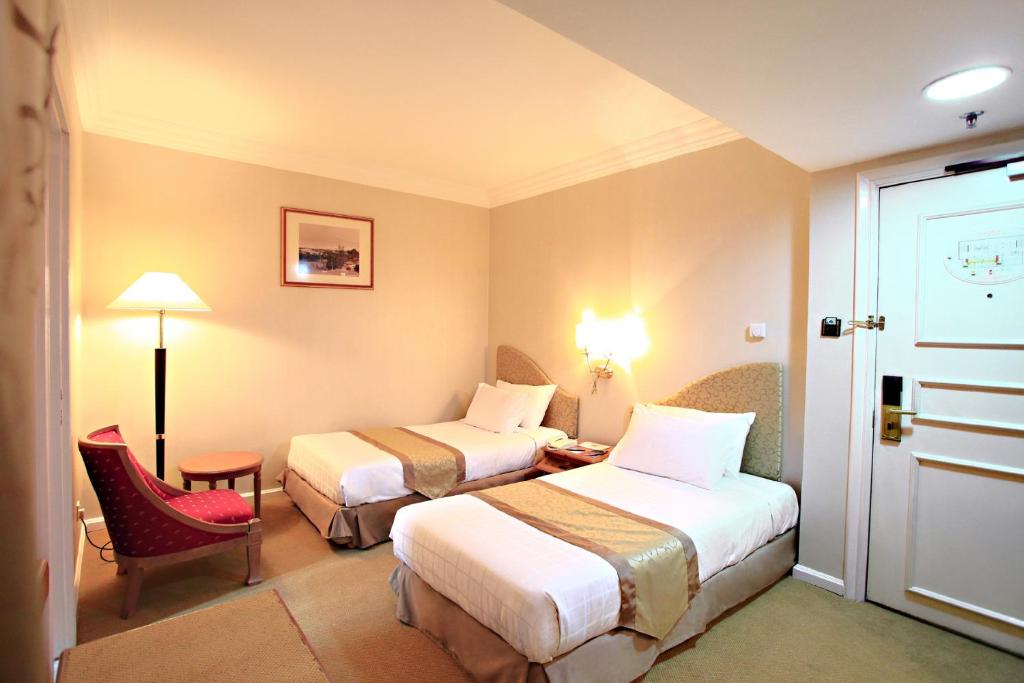 古晋梅德卡宫套房酒店的酒店客房,配有两张床和椅子