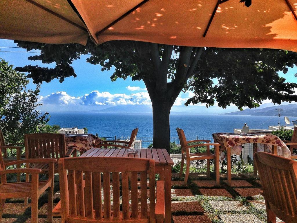 卡普里卡普里红酒酒店的一张桌子和椅子,配有雨伞和大海