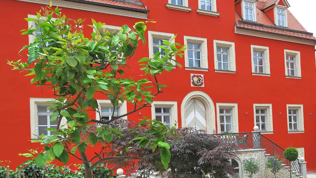 贝岑施泰因Schlosshotel Betzenstein的前面有棵树的红色建筑