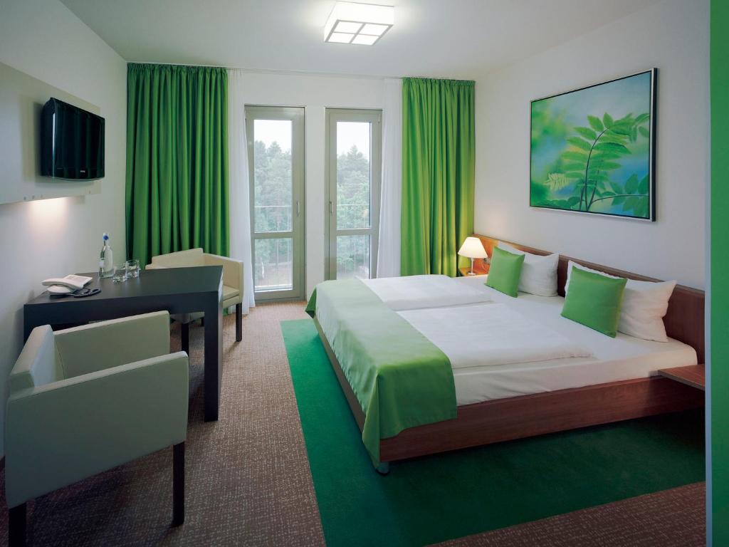 德累斯顿德累斯顿学院酒店的一间卧室配有一张床、一张书桌和绿色窗帘