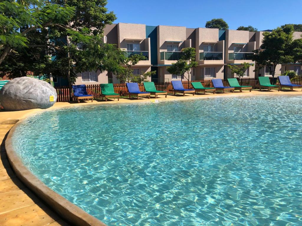 伊瓜苏港Z Hotel Boutique的一个带椅子的游泳池和一个位于酒店后面的酒店