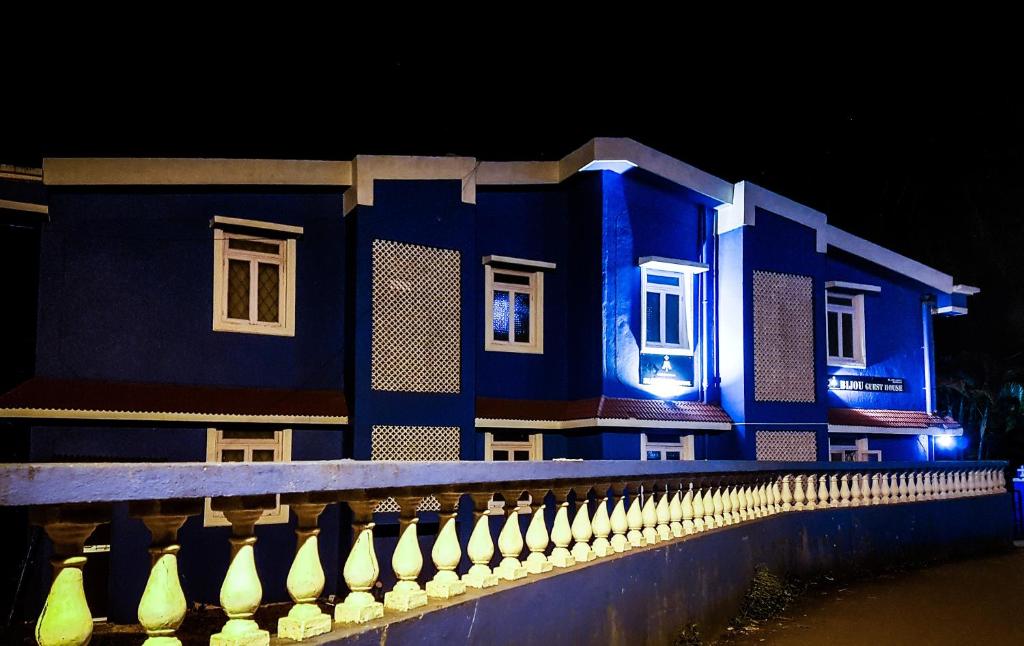 巴加Bijou Guest House的蓝色的建筑,设有白色的窗户和栅栏