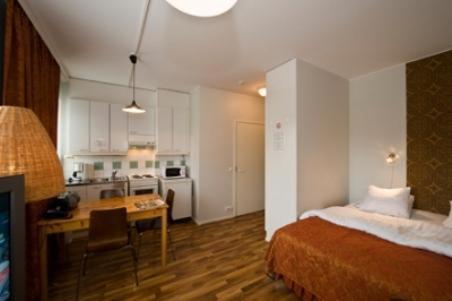 坦佩雷家园酒店的一间带一张床和一张书桌的卧室和一间厨房