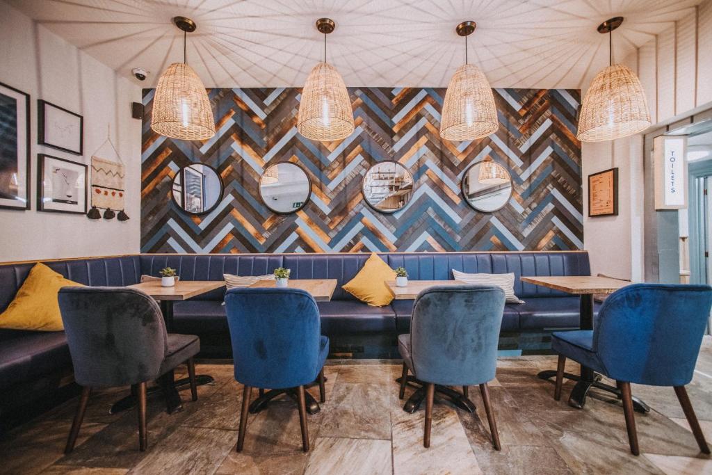锡德茅斯Dukes Inn的餐厅设有蓝色椅子和带镜子的墙壁