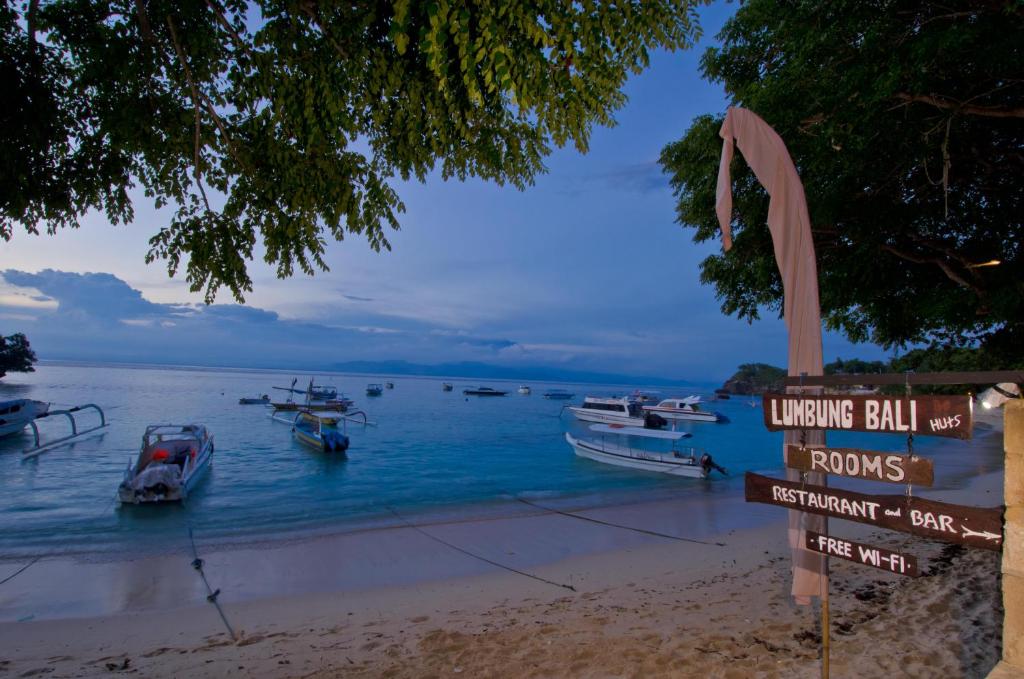 蓝梦岛郎邦巴厘岛小屋酒店的海滩上的标志,在水中划船