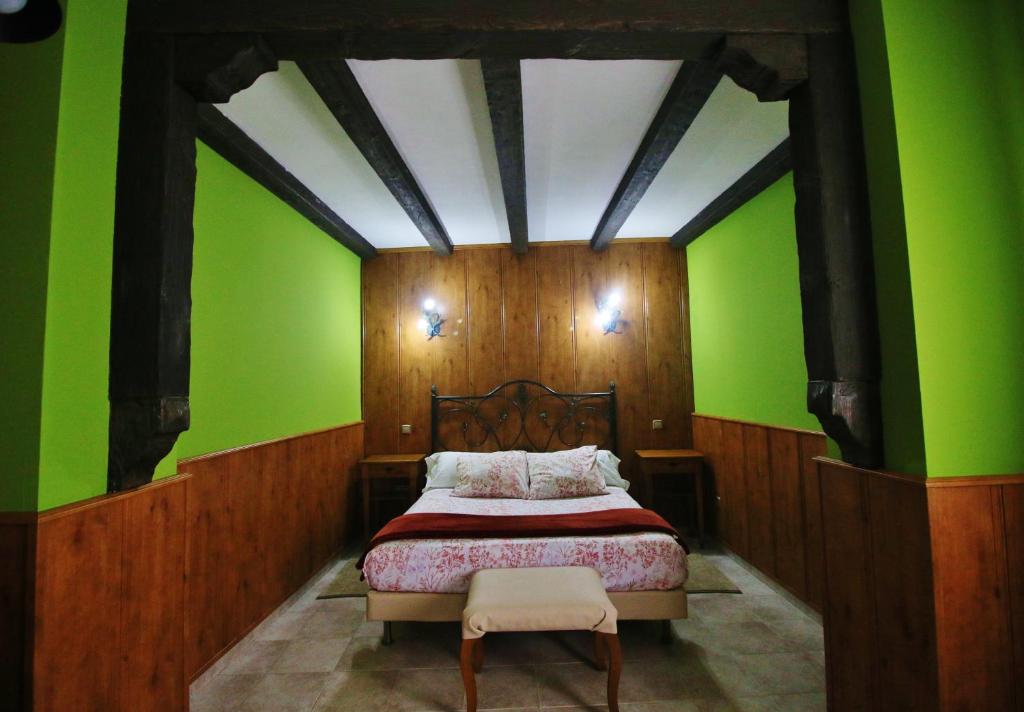 TorrelagunaPosada Del Camino Real的一间卧室设有绿色的墙壁和一张带椅子的床