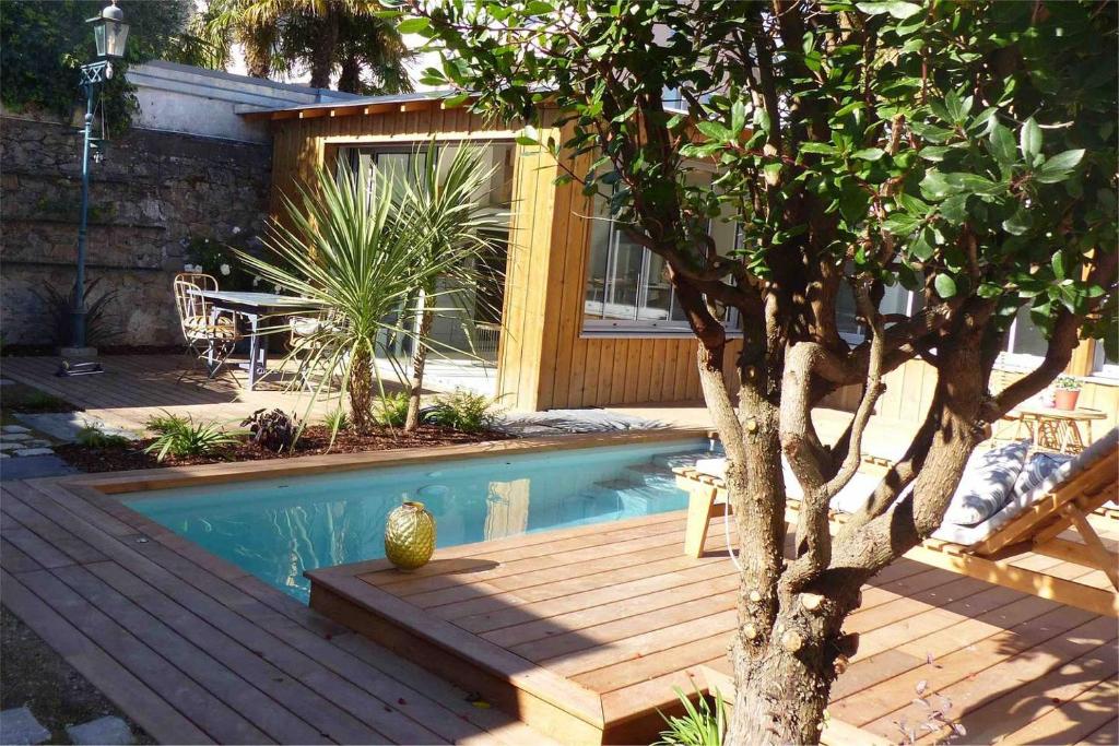 南特Le Nid du Héron, gîte urbain avec piscine chauffée的树旁的带木甲板的游泳池