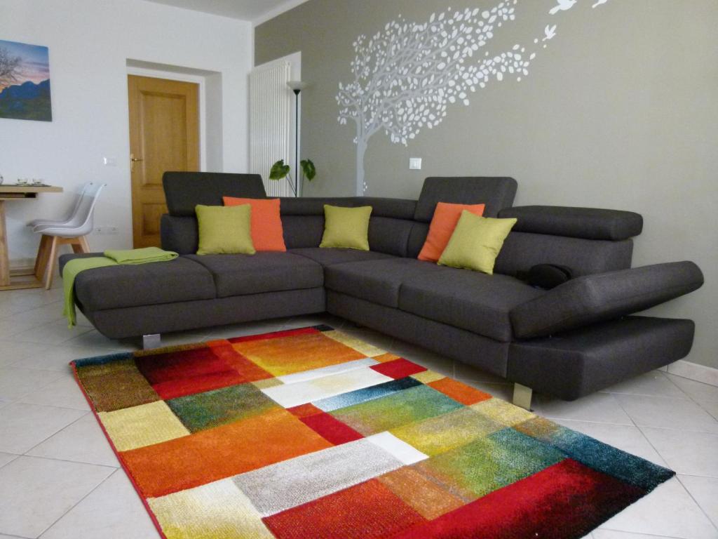 蓬泰巴Bed & Bar Mini Apartment的客厅配有黑色沙发和色彩缤纷的地毯