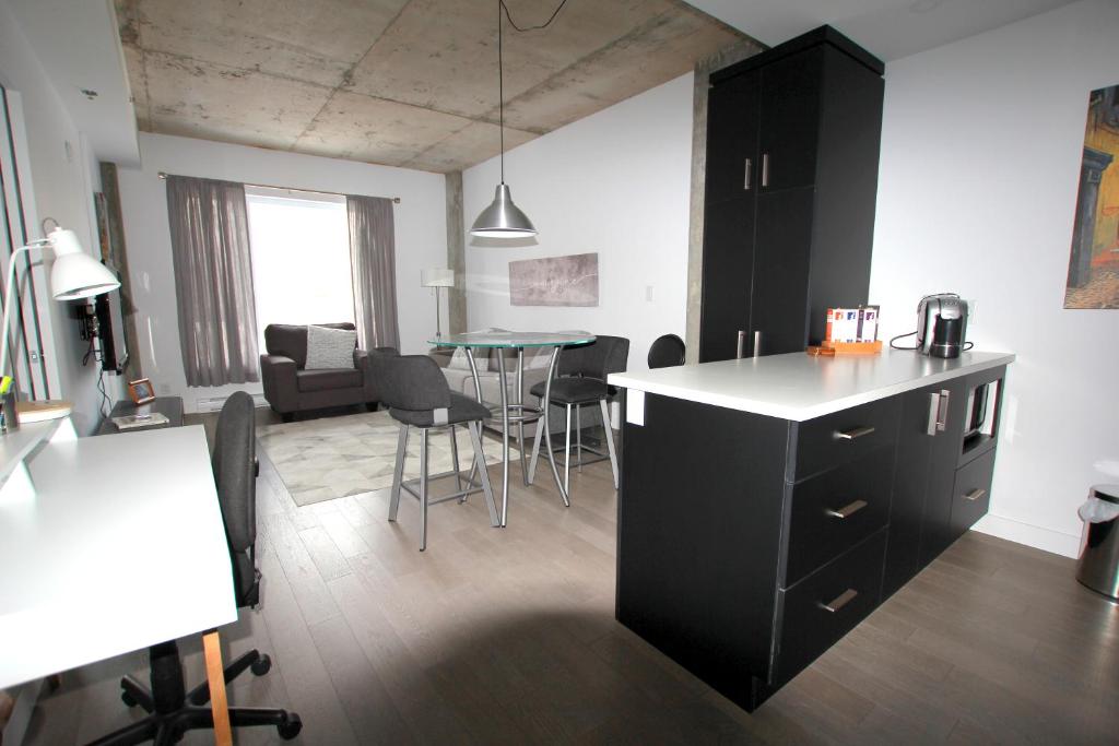 魁北克市Condo "Imagine" - stationnement privé inclus的厨房以及带桌椅的起居室。
