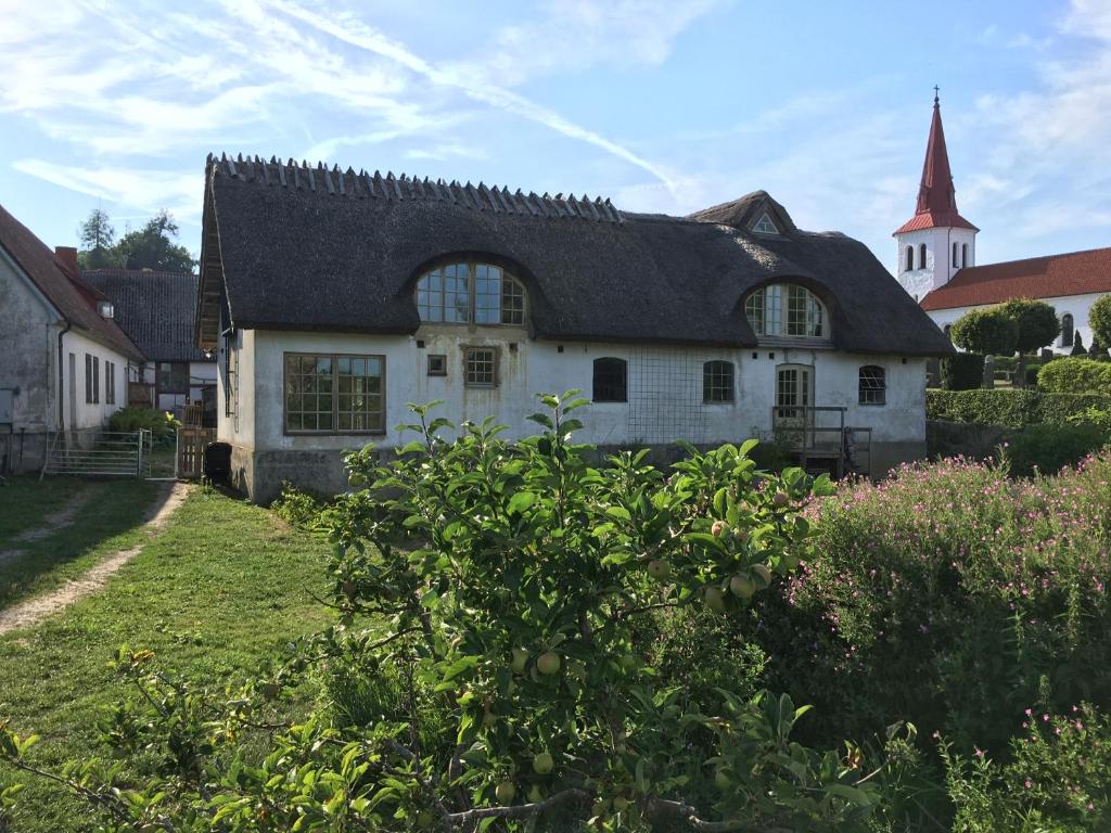 锡姆里斯港Ga Prästgården i Rörum的一座白色的房子,有黑色的屋顶和教堂