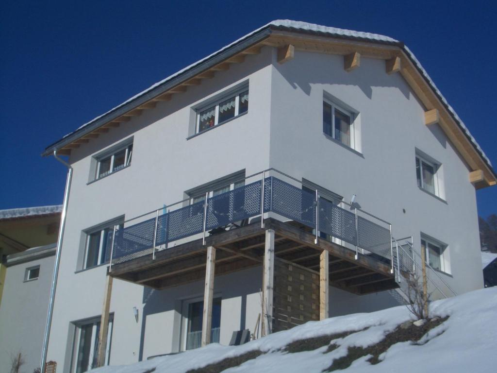弗坦Ferienwohnung Vonlanthen的雪顶上设有阳台的白色房屋