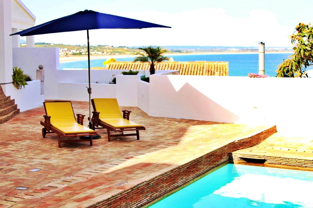 拉戈斯巴卢阿特达维拉公寓式酒店的游泳池旁的两把椅子和一把遮阳伞