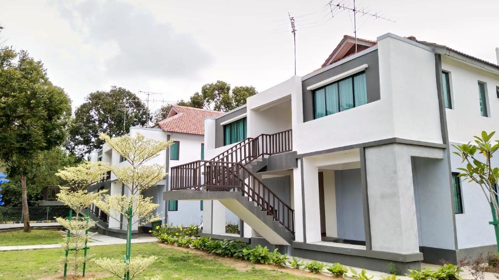迪沙鲁Desaru, Bayu Balau Beach Resort的一座白色的建筑,在院子里有楼梯