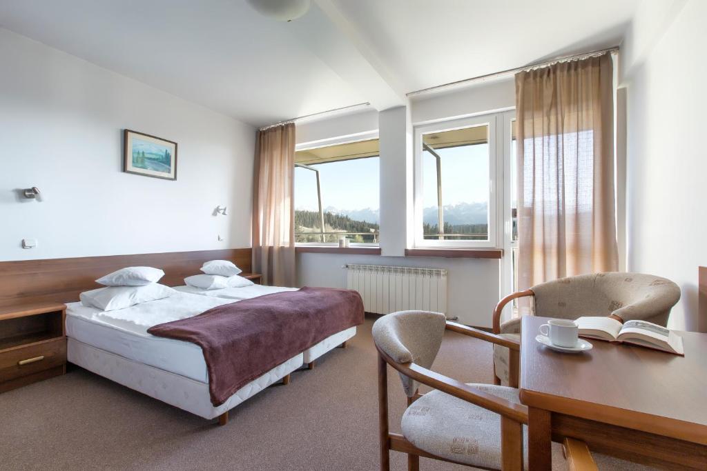 布科维纳-塔钱斯卡利斯度假村的一间卧室配有一张床、一张书桌和两个窗户。