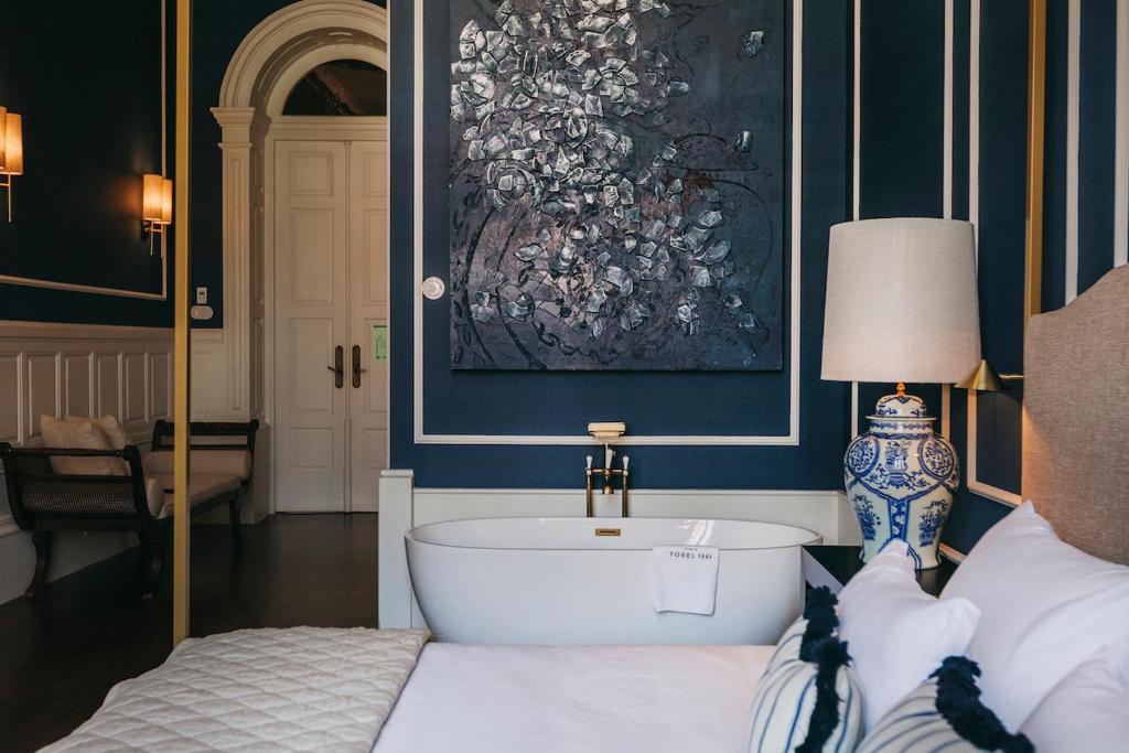 波尔图Torel 1884 Suites & Apartments的卧室配有一张床,墙上挂有绘画作品