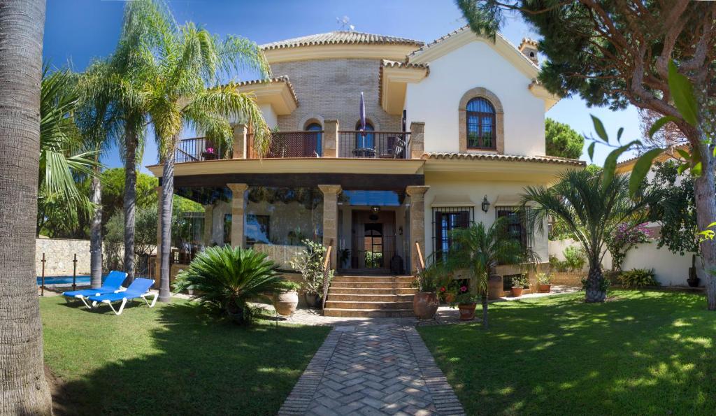 奇克拉纳－德拉弗龙特拉Hotel Azalea Playa的前面有棕榈树的房子