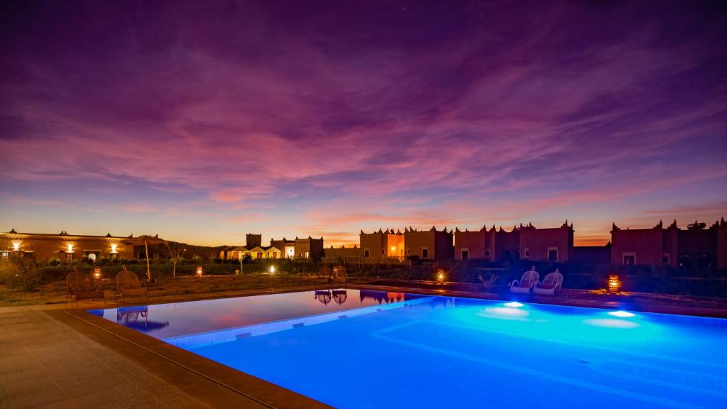 瓦尔扎扎特Ecolodge l'île de Ouarzazate的一个晚上的游泳池,以城市为背景