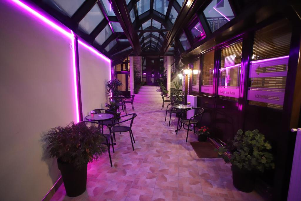 尼什Garni Hotel Laguna Lux的配有桌椅和紫色灯的房间