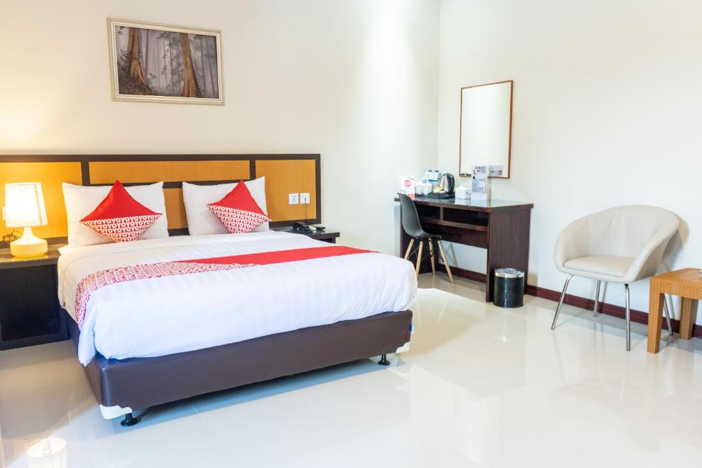 秾莎Hokkie Hotel Punggur Batam的一间卧室配有一张床、一张桌子和一把椅子