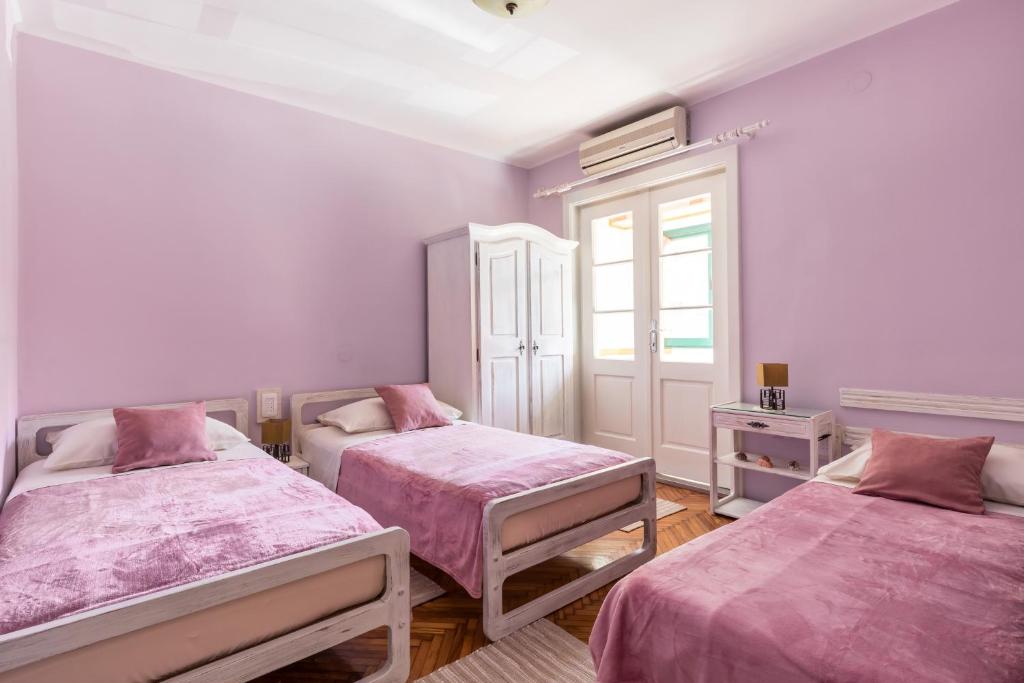 斯普利特Sunny Apartment Split的客房设有两张带粉色床单的床和窗户。