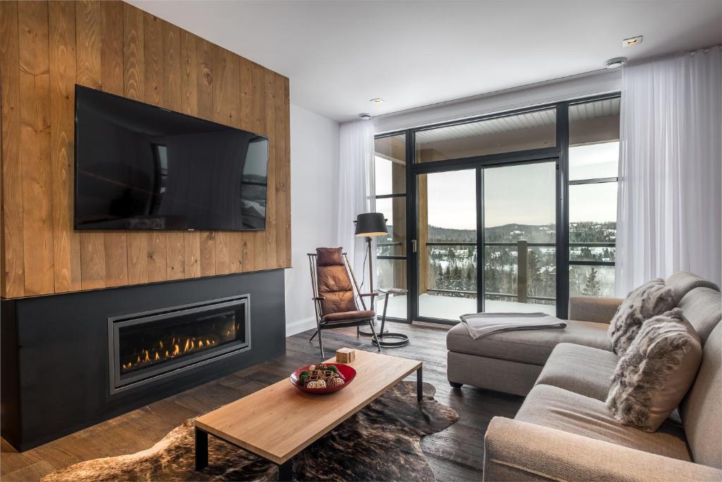 蒙特朗布朗Horizon 104 by Tremblant Prestige的客厅设有壁炉和电视。