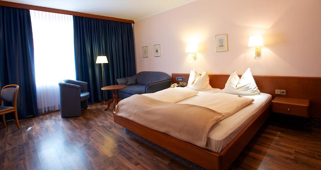 慕尼黑卡姆酒店的酒店客房带一张大床和一把椅子