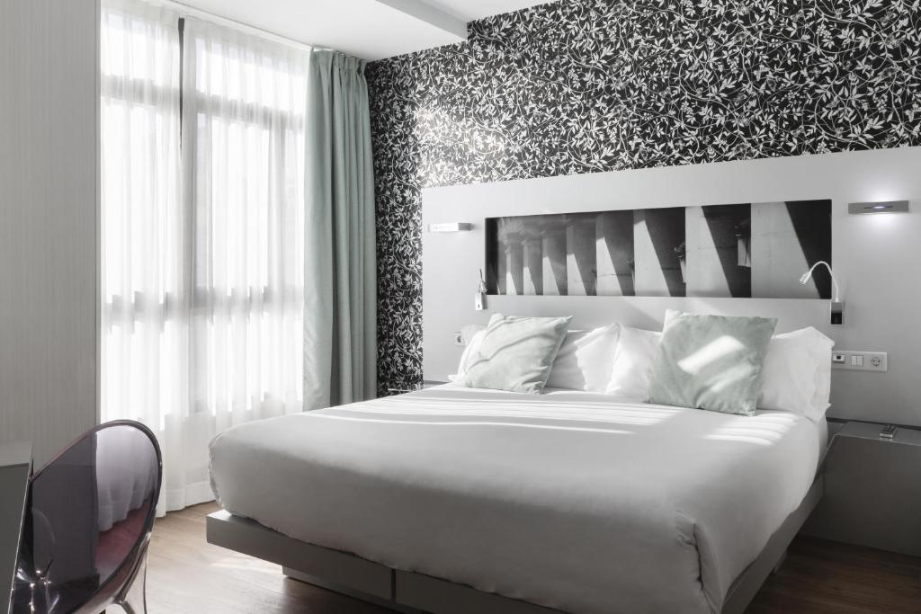 马德里马约尔广场小宫殿酒店的卧室配有白色的床和花卉装饰墙