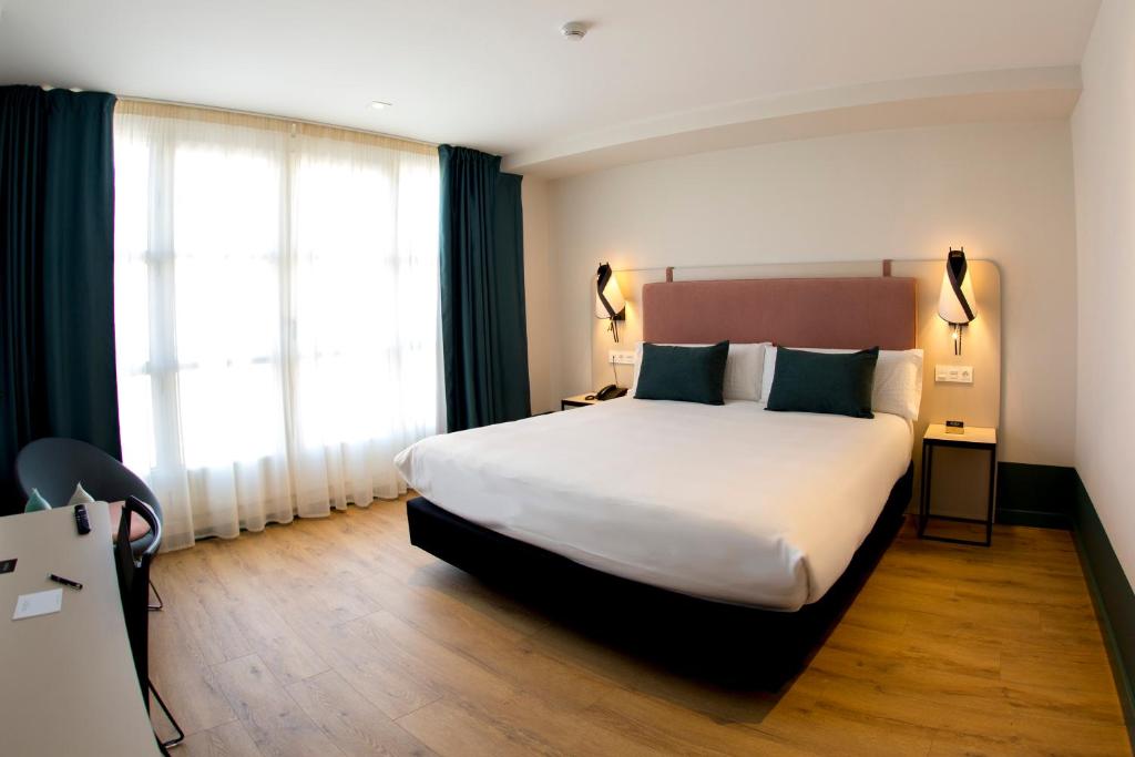 哈罗Hotel Plaza De La Paz的酒店客房设有一张大床和两个窗户。