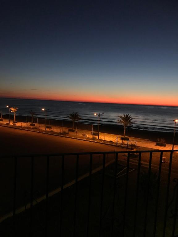 珀特萨普拉亚Apartamento PortSaplaya的日落时分拥有棕榈树和海洋的海滩