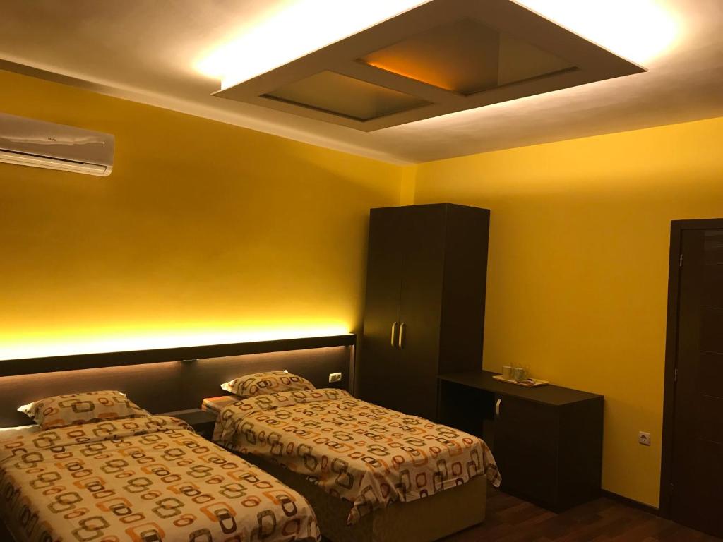 普列文Център的两张床位于带黄色墙壁的酒店客房