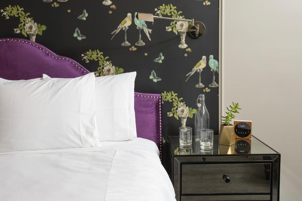 芝加哥柳条公园酒店的一间卧室配有一张带紫色床头板和边桌的床