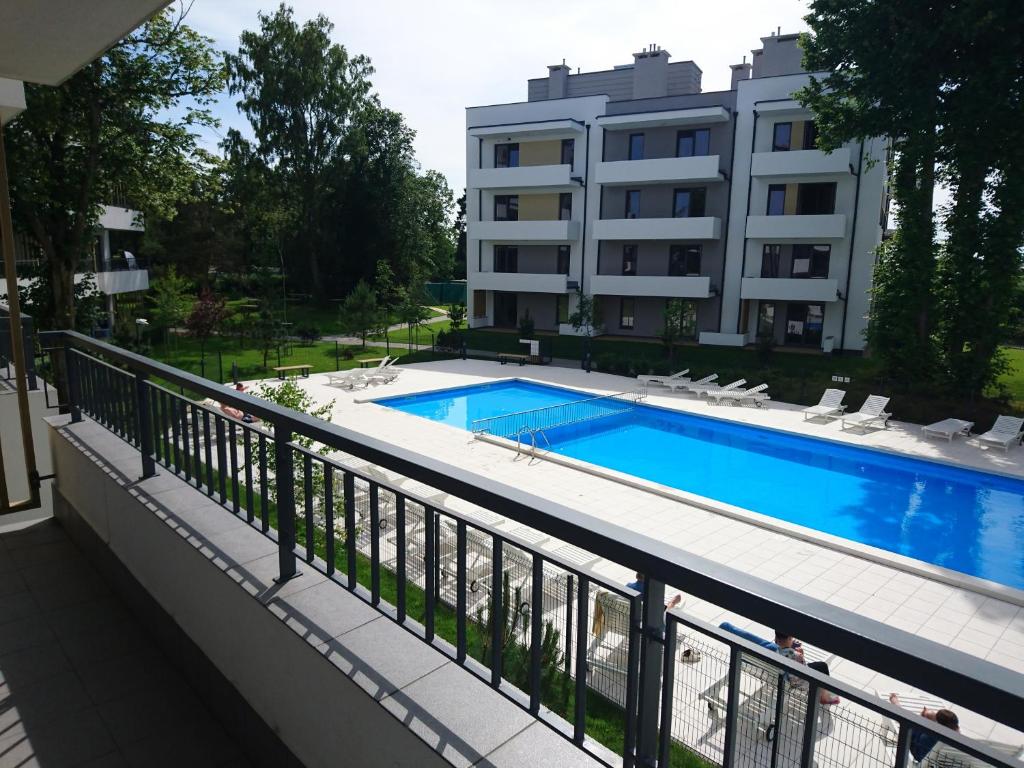尤斯托尼莫斯基Apartament 13 Ustronie Morskie的一个带游泳池和大楼的阳台