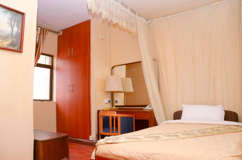 坎帕拉Fang Fang Hotel的配有一张床和一张书桌的酒店客房