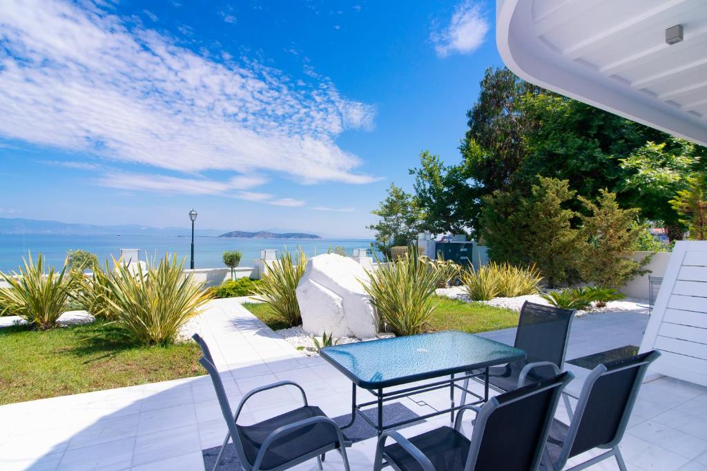 萨索斯Mythodea Apartments的一个带桌椅的庭院和大海