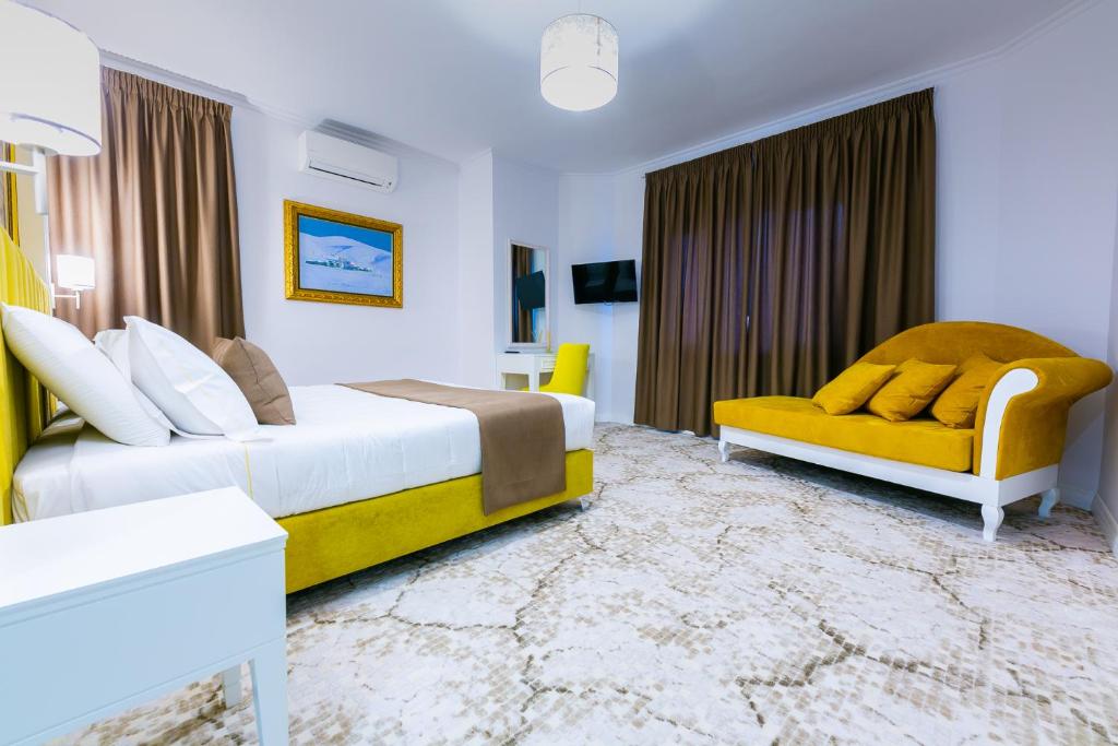 地拉那ART Hotel Tirana的酒店客房带两张床和一张黄色沙发