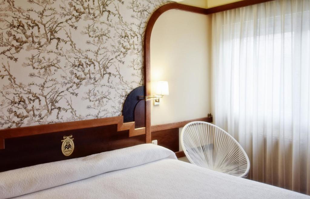 布尔戈斯马日亚路易撒酒店的卧室配有白色的床和风扇