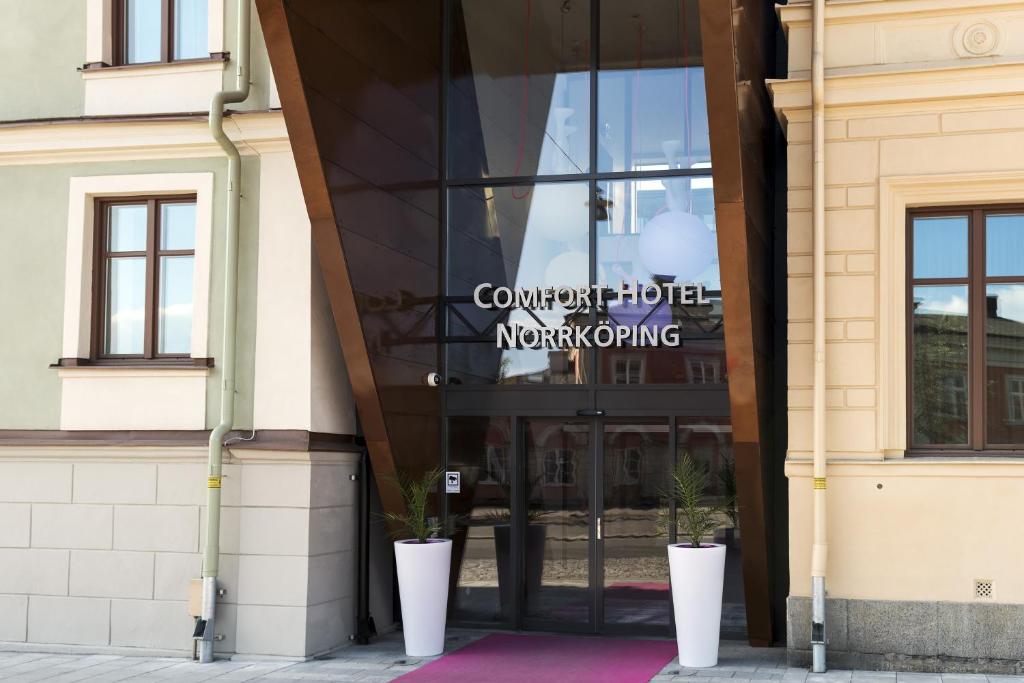 诺尔雪平诺尔雪平舒适酒店的前方有两棵盆栽植物的建筑的玻璃门